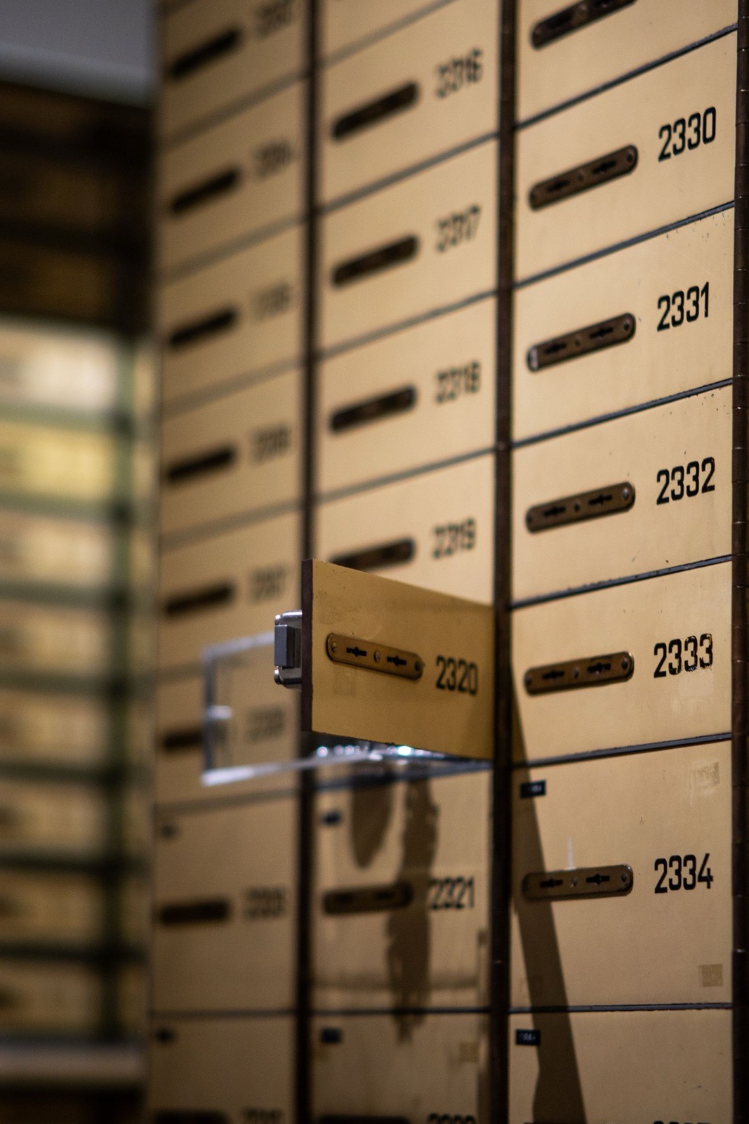 Wall of numbered safe-deposit boxes with a single box pulled out of its row.
