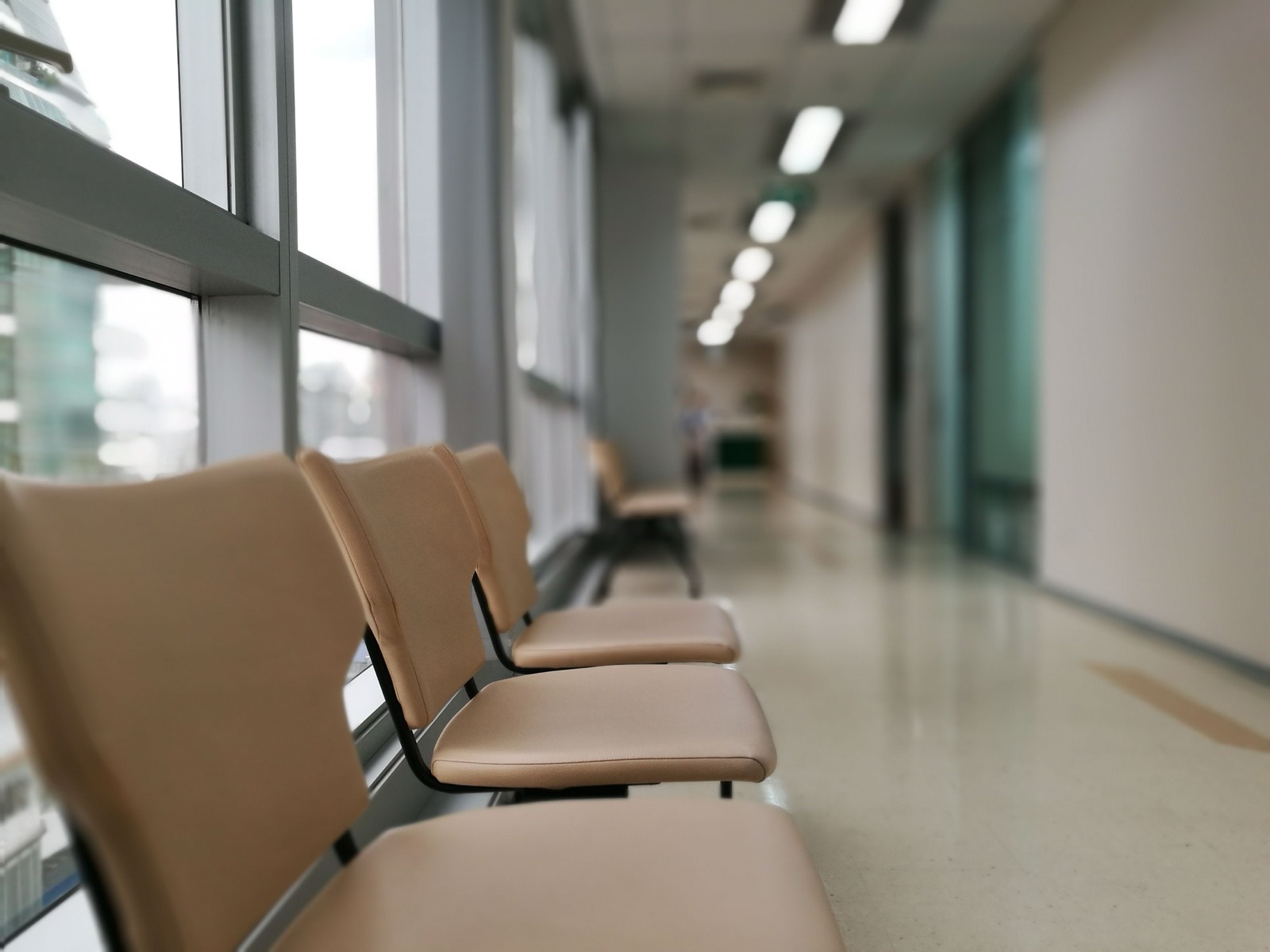 A quiet clinical corridor with empty seating and daylight.